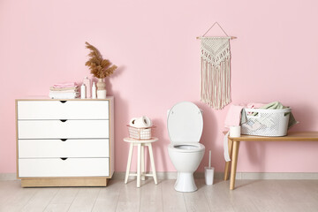 Stylish interior of modern restroom with ceramic toilet bowl and paper rolls