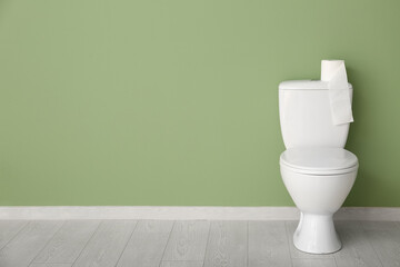 Roll of paper on toilet tank near color wall