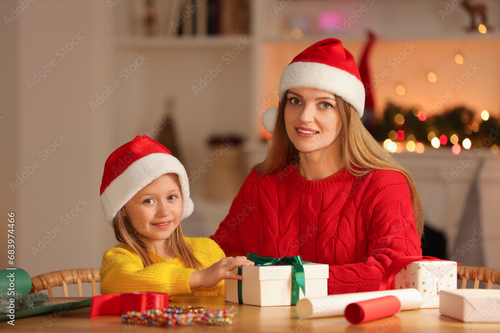 Wall mural Christmas presents wrapping. Mother and her little daughter with gift box at table in room