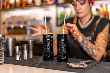 Bartender with two cocktails with straws ready to serve