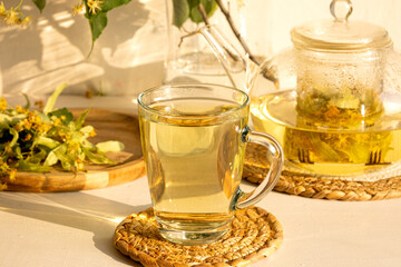 Linden flower tea in the transparent glass cup with tea spoon on a background 