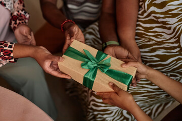 Closeup image of family giving Zawadi gift to little girl at Kwanzaa celebration