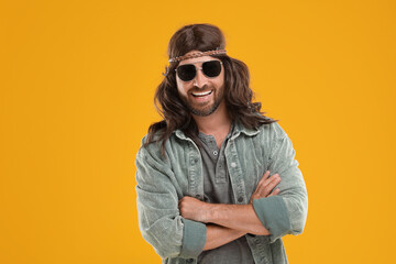 Stylish hippie man in sunglasses on orange background