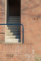 An entrance to a brick building with stairs and railing