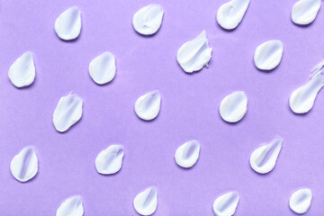 Composition with smears of cream on lilac background