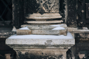 The lower part of an old column with snow. Fragment of the Boim chapel in Lviv, Ukraine. Old Renaissance architecture. Decorative details and elements close-up.