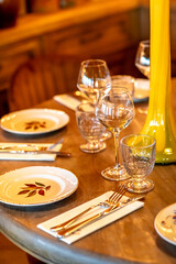 Wooden table in the restaurant with plates, wine glasses and cutlery