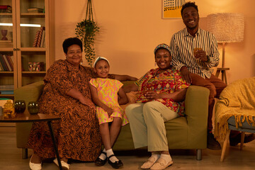 Fototapeta na wymiar Happy family of four spending evening at home together, resting on couch and enjoying soft drinks