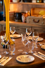 Wooden table in the restaurant with plates, wine glasses and cutlery