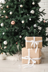 Fototapeta na wymiar Beautiful Christmas tree with gift boxes near white brick wall
