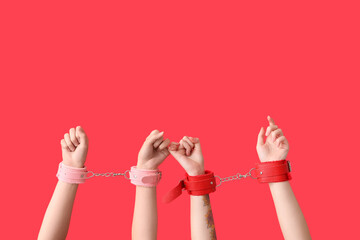 Female hands in handcuffs from sex shop on red background