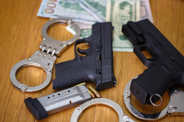 two semi automatic pistols with handcuffs, bullet shells 9 mm and American dollar banknotes on...