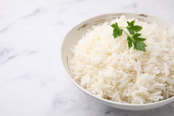 Bowl of delicious rice with parsley on light table, closeup. Space for text