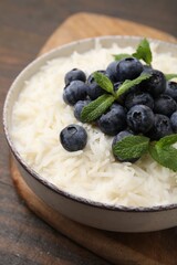 Bowl of delicious rice porridge with blueberries and mint on table, closeup