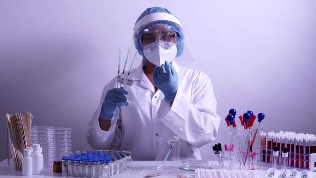 Medical Nurse in safety gloves and protective mask is holding syringes with vaccine Injection and calling for vaccination. Fully equipped health care worker in the immunisation clinic or hospital.