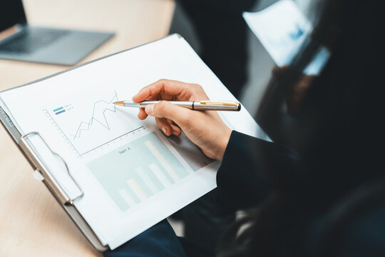 Closeup imaged of skilled businesswoman hand comparing between green and blue graph. Smart female leader hand writing on business statistic graph show increasing sales. Focus on hand. Ornamented.