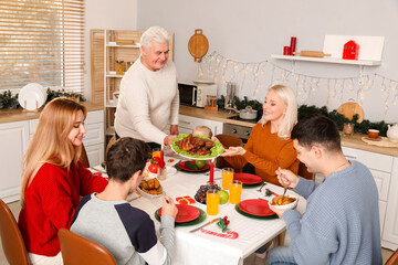Mature man having Christmas dinner with his family in kitchen