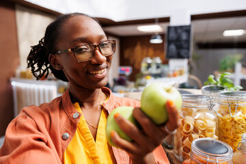 POV of an African American woman promoting eco friendly, organic products like green apples, at a...