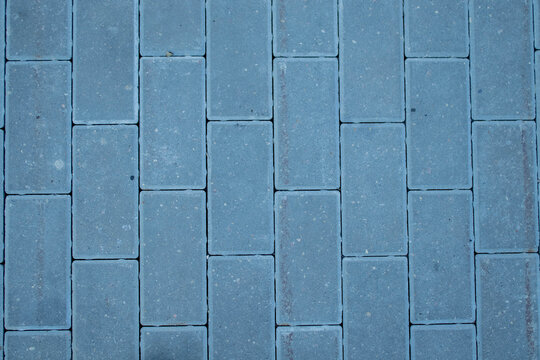 View of the paving slabs. The tiles are laid in even rows, top view. Gray paving slabs, diagonal view.