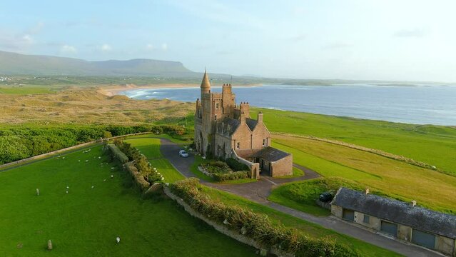 Spectacular aerial orbit sunset view of Mullaghmore Head with huge waves rolling ashore. Awe scenery with magnificent Classiebawn Castle. Signature point of the Wild Atlantic Way, Co. Sligo, Ireland