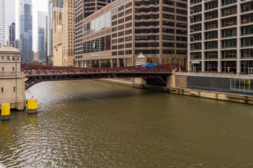 a beautiful autumn landscape with people walking and cars driving over the Monroe Street bridge over the Chicago River and skyscrapers, office buildings and hotels in Chicago Illinois USA