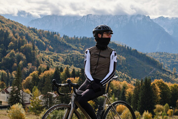 Close-up photo of man cyclist wearing full cycling winter kit and helmet. Man cyclist standing...