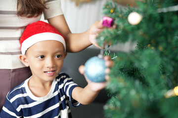 Merry Christmas 2024 concept Mother and child decorate the Christmas tree with colorful Christmas balls.