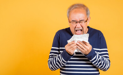 Pensioner unwell. Asian older man cold having flu and sneezing from sickness virus problem use...