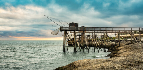 Traditional fisherman hut on stilts with carrelet fishing net. Typical wooden houses for fishing at beach © Ievgen Skrypko