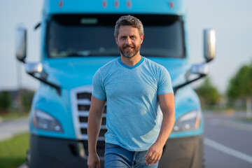 Men driver near lorry truck. Man owner truck driver in t-shirt near truck. Handsome middle aged man trucker trucking owner. Semi trailer, semi trucks. Handsome man posing in front of truck.