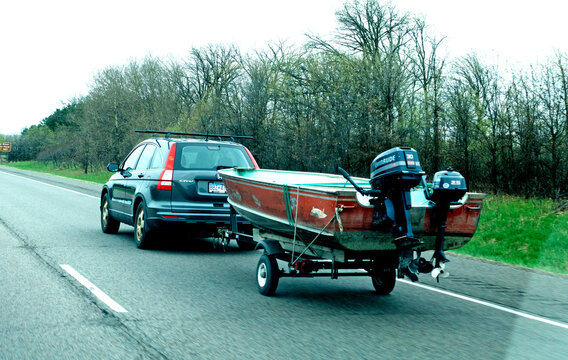 Car hauling Lund aluminum boat with a larger Evinrude outboard motor for speed and a smaller engine for trolling. Minnesota MN USA