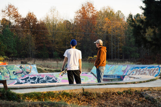 Two Skateboarders at a Graffiti-Adorned Skatepark Engaging in Conversation with a Focus on Skateboarding Culture and Community - Powered by Adobe