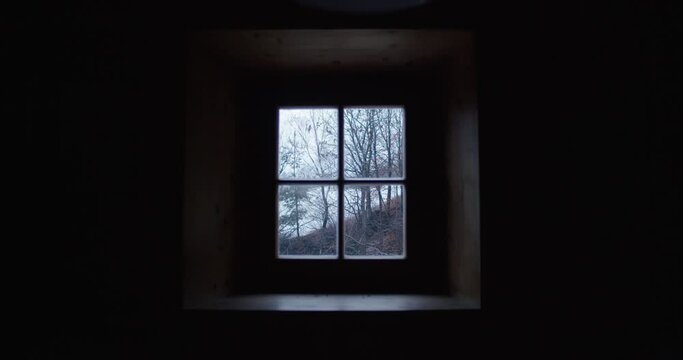 a small wooden window in a cabin frames a winter landscape 