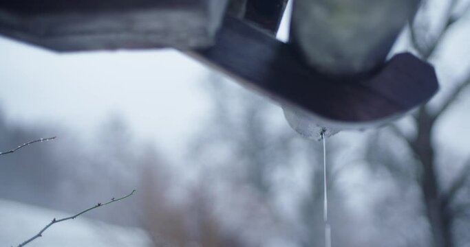 a closure on a gutter dripping water on a foggy winter day