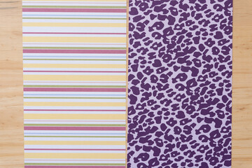 wide scrapbook paper sheets (one with stripes and the other with animal skin pattern or spots) on wood