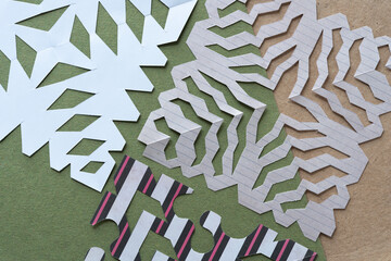 various decorative paper designs mimicking the delicate patterns of snowflakes on rough green and...