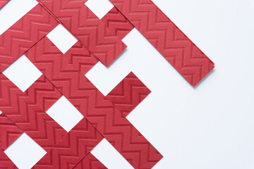 overlapping red paper stripes with embossed chevron or zig zag pattern on white paper