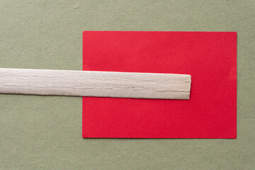 paper background composed of bookbinding spine stiffener or stripe, rough green scrapbooking paper sheet, and blank red card