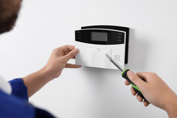 Man installing home security alarm system on white wall indoors, closeup - obrazy, fototapety, plakaty