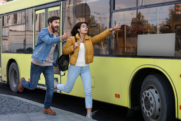 Being late. Worried couple running towards bus outdoors, space for text