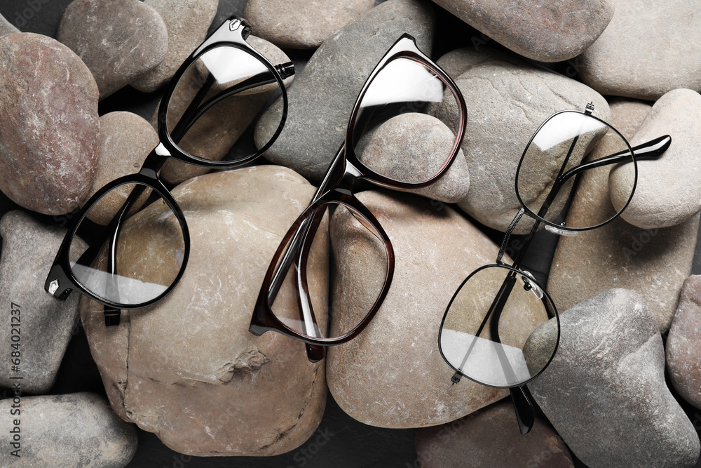 Wall mural Glasses in stylish frames on stones, top view