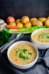 Bowls of German Potato Soup (Kartoffelsuppe) Garnished with Parsley: Bowls of vegetable soup with potatoes, celery, carrots , and garlic