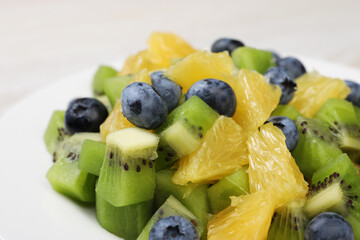 Fresh tasty fruit salad on plate, closeup