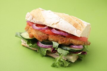 Delicious sandwich with schnitzel on green background, closeup