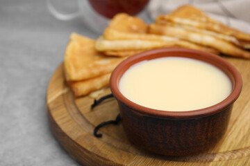 Tasty condensed milk and crepes on grey table, closeup