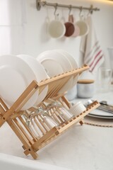 Fototapeta na wymiar Drying rack with clean dishes on light marble countertop in kitchen