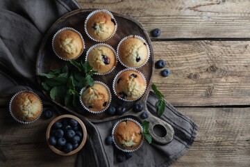 Obraz na płótnie Canvas Delicious sweet muffins with blueberries and mint on wooden table, flat lay. Space for text
