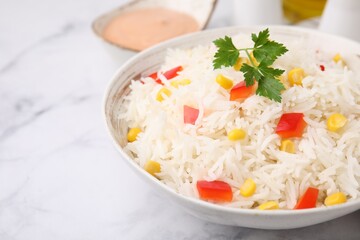 Bowl of delicious rice with vegetables and parsley on light table, closeup