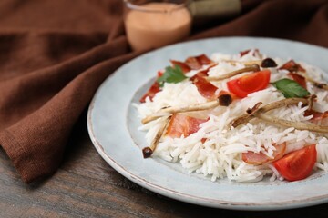 Delicious rice with bacon, mushrooms and tomatoes on table, closeup