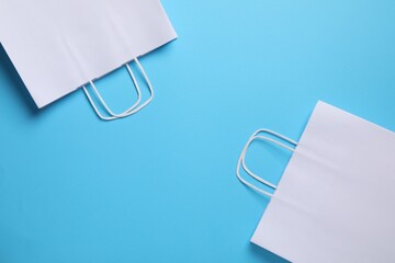 White paper bags on light blue background, top view. Space for text